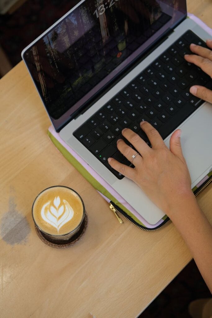 A person working on a laptop with a latte nearby, creating a cozy and productive environment.