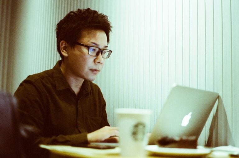 a man sitting at a table using a laptop computer