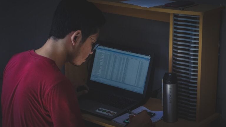 man in red shirt using black laptop computer