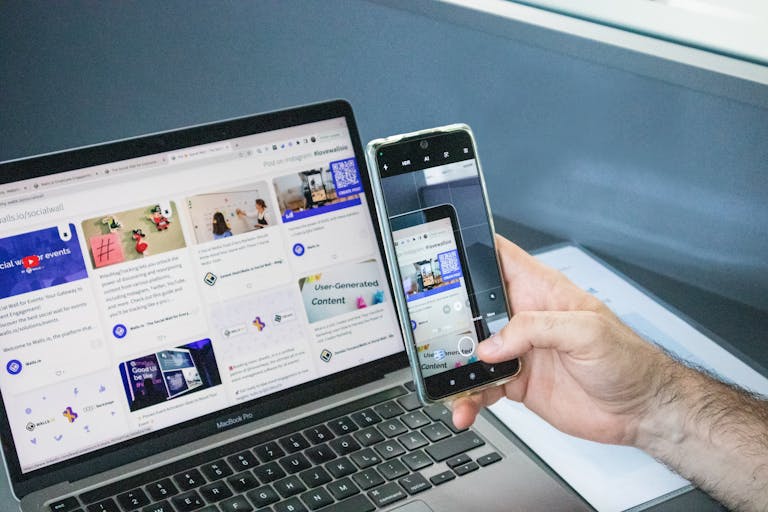 Close-up of a smartphone capturing a laptop screen, representing technology integration.