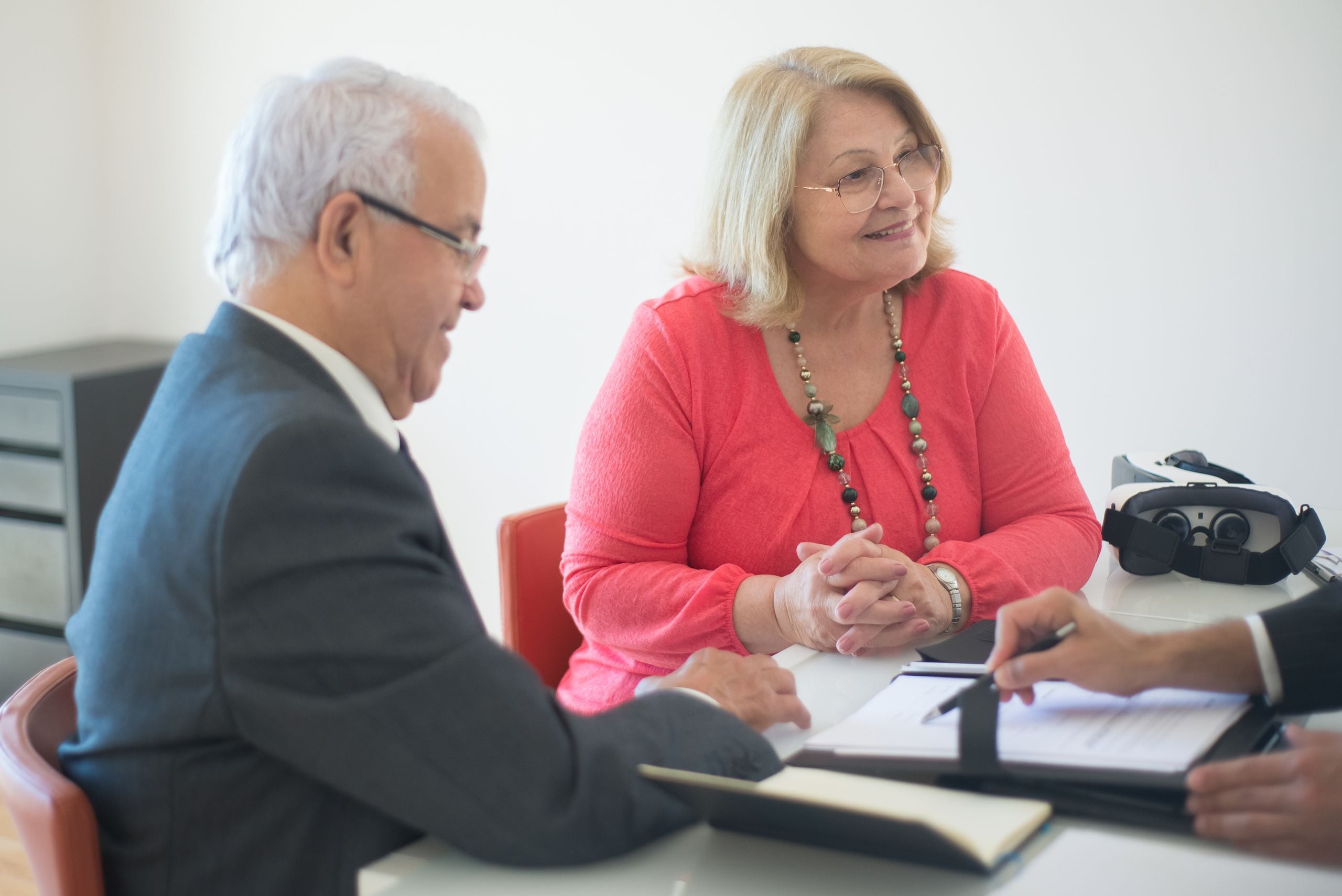 Elderly couple with real estate agent at a meeting discussing property investment and mortgage options.